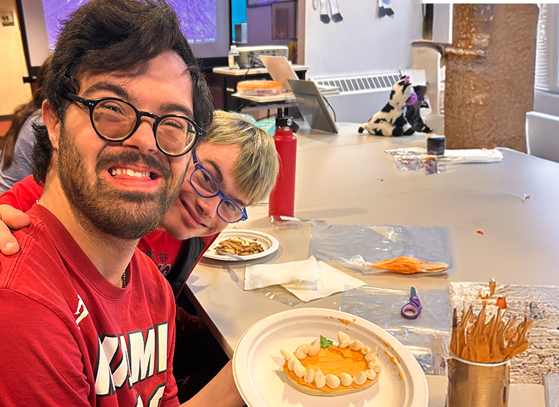 Photo of two young adults smiling doing arts and crafts 