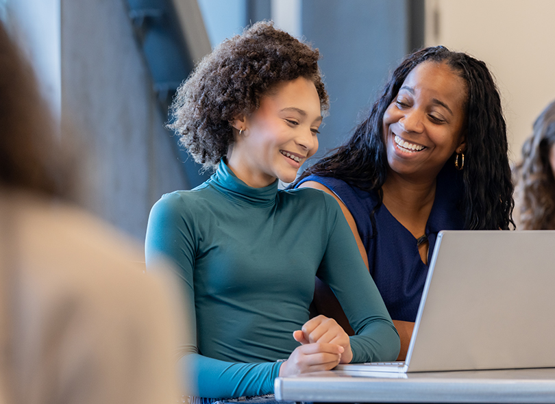 Two girls smiling at computer screen 