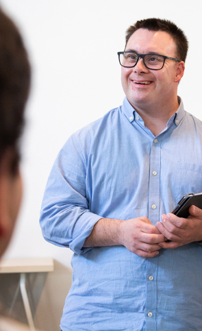 Photo of young adult male smiling in a work environment