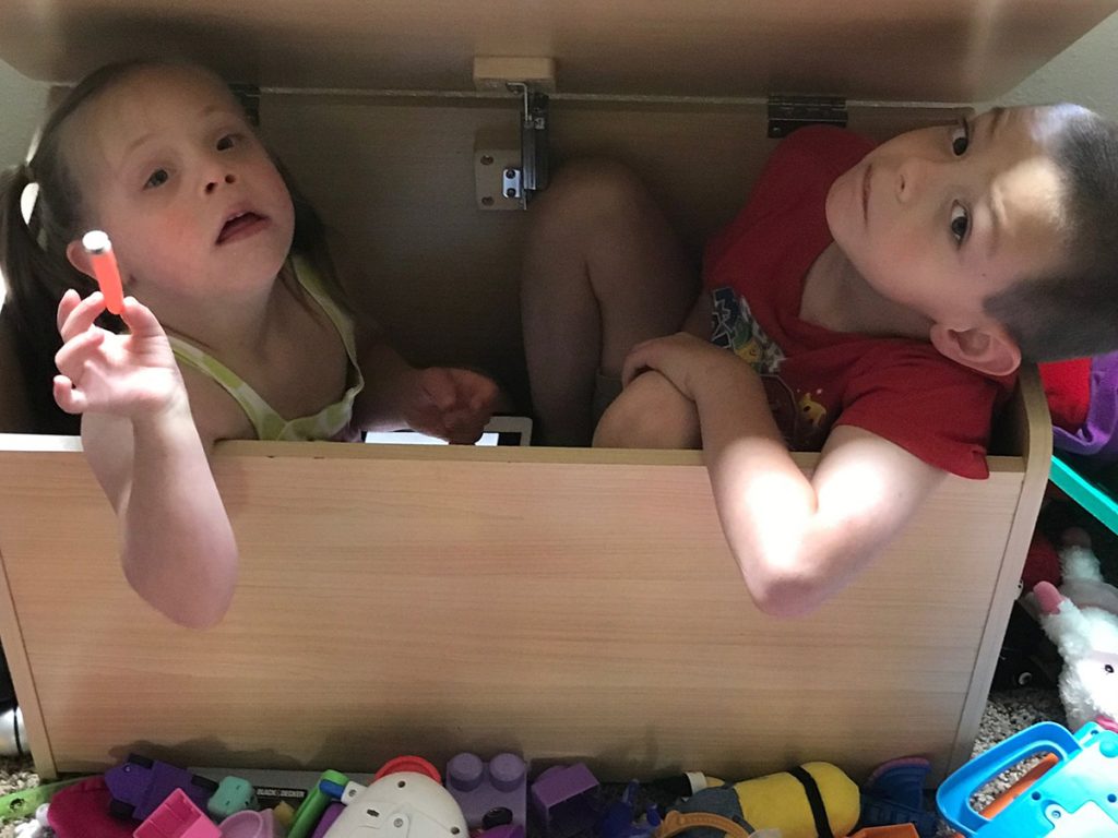 Siblings playing in a toy box.
