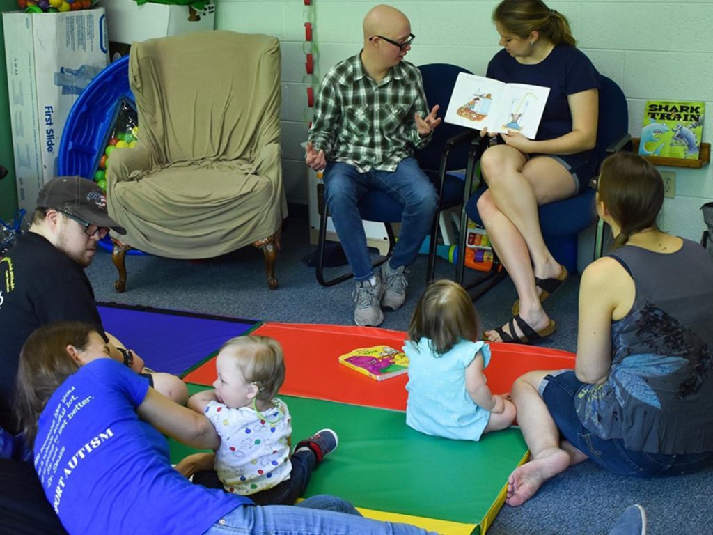 Adults leading a children's reading circle.